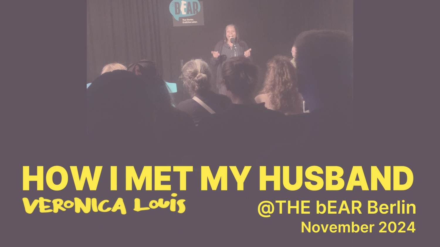 Storyteller Veronica Louis speaking in a mic in front of a sitting audience.